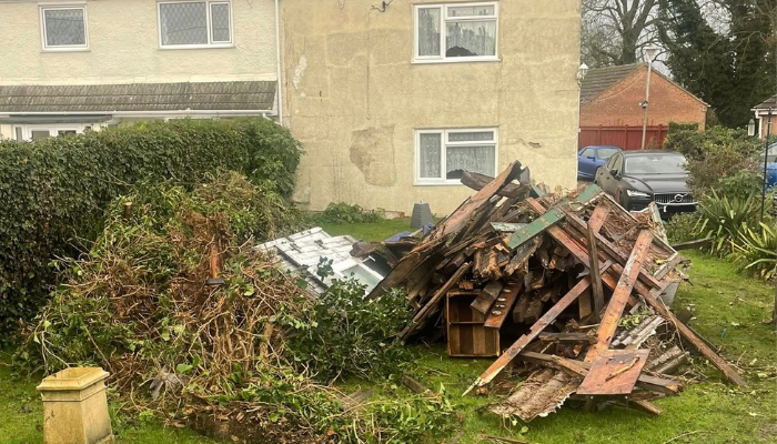 A back garden with wood, stone and a tree laid in view